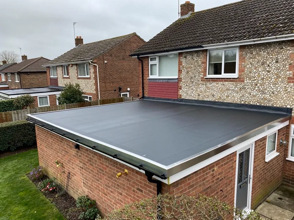 A new dark grey EPDM rubber flat roof on a single-storey brick rear extension with aluminium edge trim