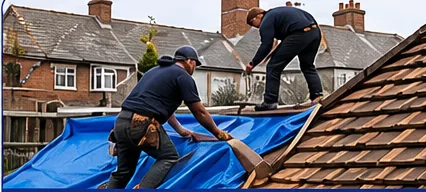 Roofers securing a tarpaulin over a damaged roof